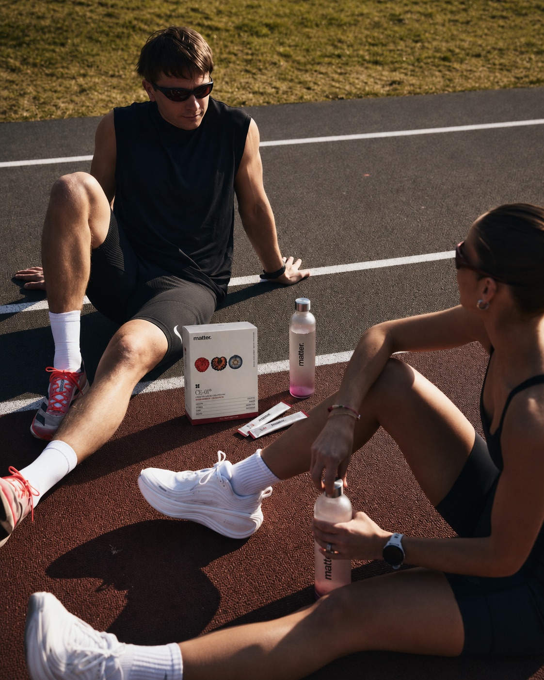 Two runners resting on a track beside a CE-01 box